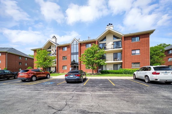 Front view of a multi-story apartment building with brick facade and balconies.