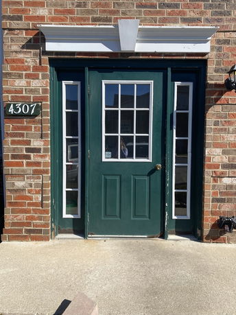 Front view of a building entrance with a green door and brick exterior.
