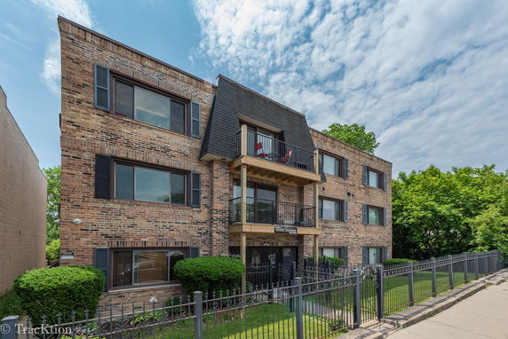 Front view of a three-story brick apartment building with balconies.