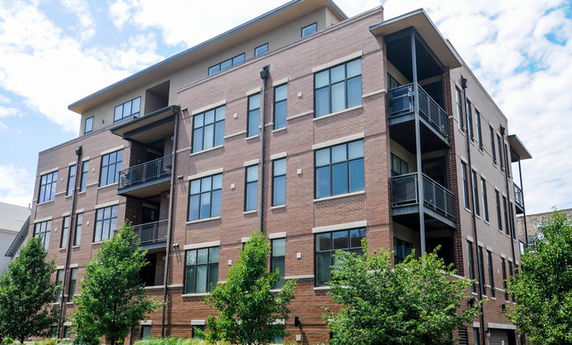 Front view of a multi-story brick apartment building with balconies.