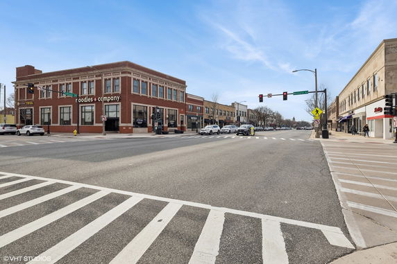 Street view of a two-story commercial building with storefronts and large windows.