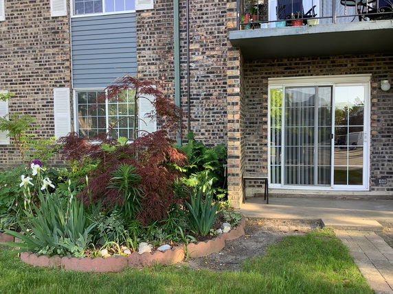 Front view of a brick house with sliding glass doors and a small patio area.