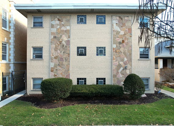 Front view of a three-story apartment building with a brick facade and stone accents.