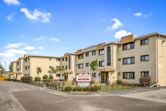 Front view of a multi-story condominium building with a brick exterior and multiple windows.