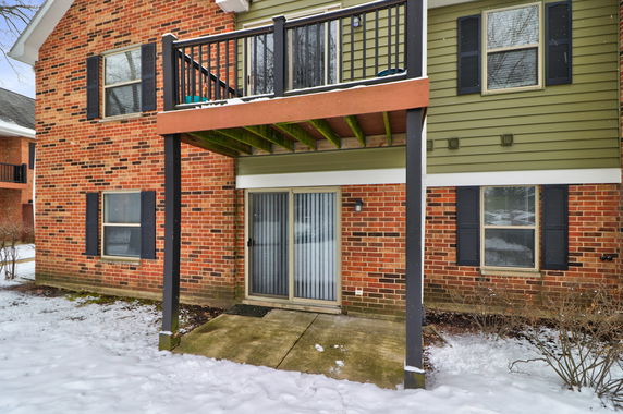 Front view of a brick house with a balcony and sliding glass door on the ground level.