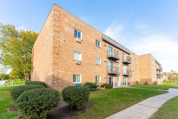 Front view of a three-story brick apartment building with small balconies.