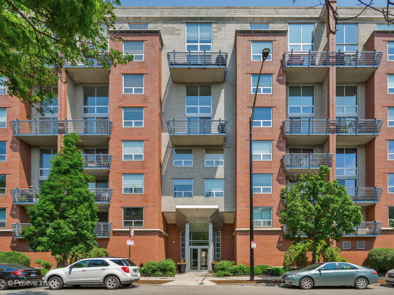 Front view of a multi-story residential building with balconies and red brick facade.