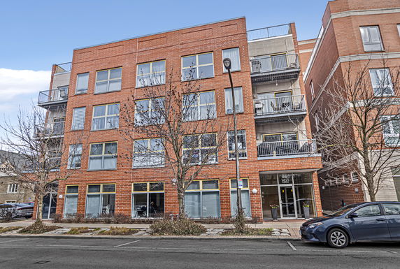 Front view of a multi-story brick apartment building with balconies.