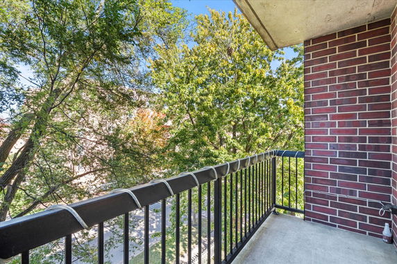 Balcony view with trees and a brick wall