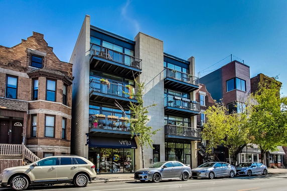 Front view of a modern four-story building with balconies and large windows.