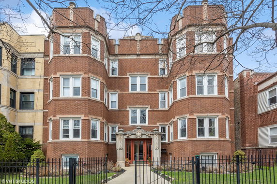 Front view of a brick multi-story residential building with decorative entrance.
