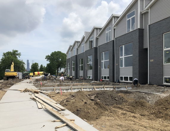 Front view of a row of townhouses under construction.