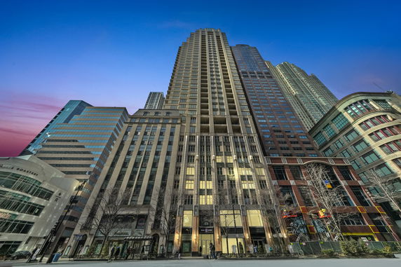 Front view of a tall skyscraper surrounded by other buildings.