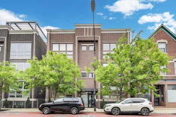 Front view of a multi-story brick building with large windows.