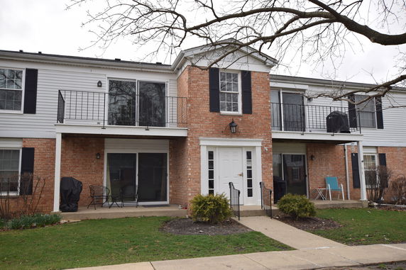 Front view of a two-story brick house with multiple balconies and large windows.