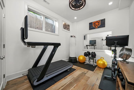 Indoor home gym with a treadmill, exercise bike, weights, and exercise ball.