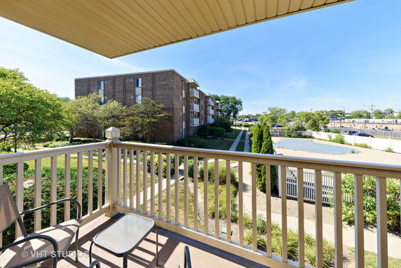 View from a balcony overlooking a multi-story brick building and surrounding area.