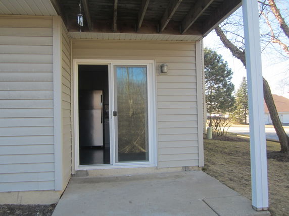 Front view of a house with sliding glass door and beige siding.