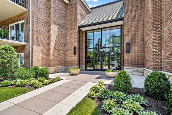 Front view of a building entrance with large glass doors and brick exterior.