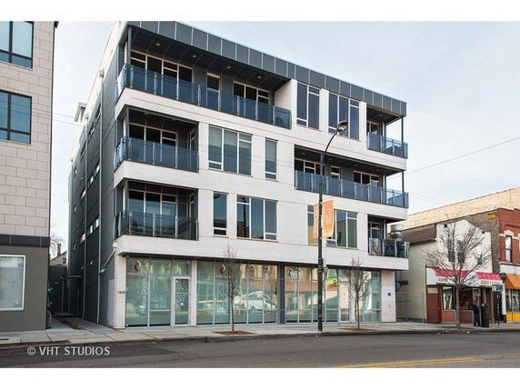Front view of a modern multi-story building with large windows and balconies.