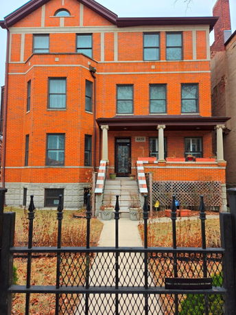 Front view of a multi-story brick house with steps leading to the entrance.