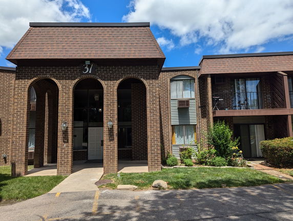 Front view of a multi-story building with arched entrances and brown brick facade.