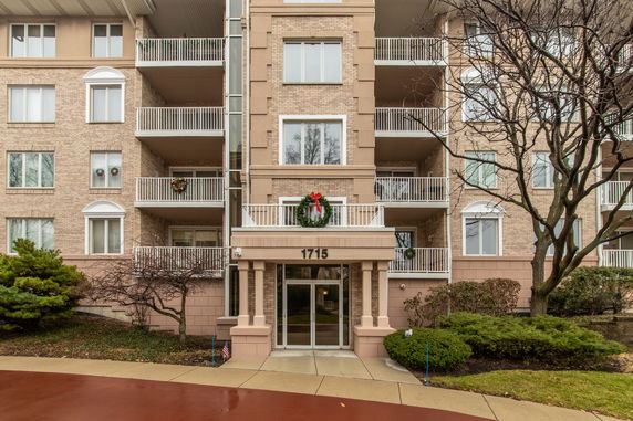 Front view of a multi-story apartment building with balconies and decorative wreaths.
