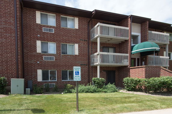 Front view of a brick apartment building with balconies and an entrance.