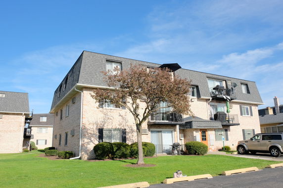 Front view of a multi-story residential building with balconies and a sloped roof.