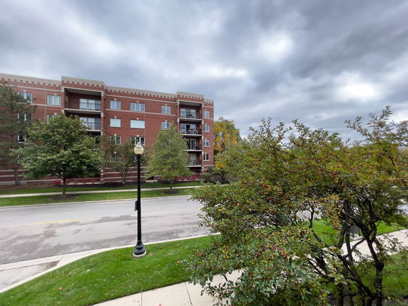 Front view of a multi-story brick apartment building with balconies.