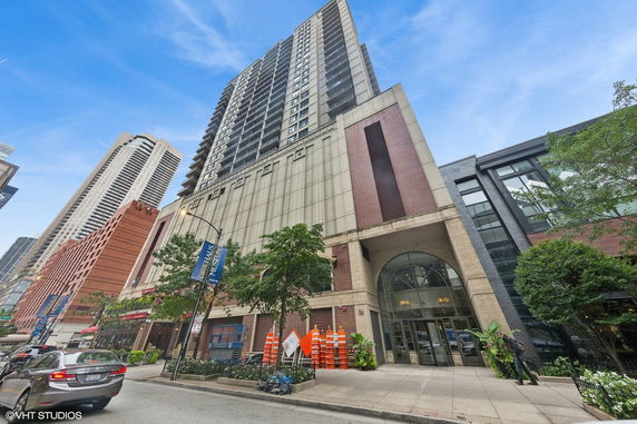 Front view of a tall multi-story building with large entrance and surrounding urban environment.