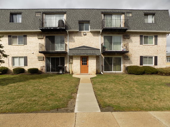 Front view of a multi-story brick building with balconies.