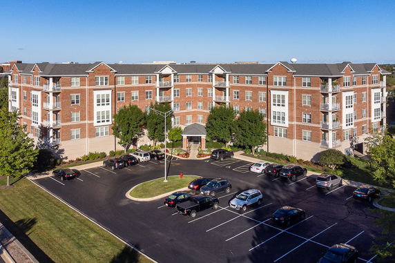 Front view of a multi-story apartment building with a parking area in the foreground.