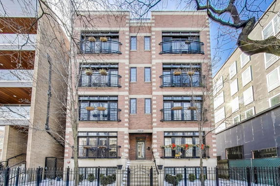 Front view of a multi-story brick apartment building with balconies and decorative railings.