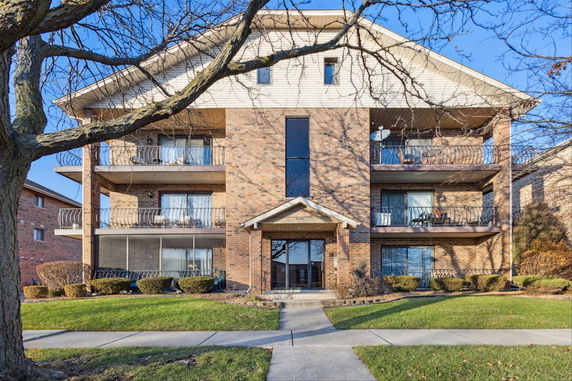 Front view of a multi-story brick apartment building with balconies.
