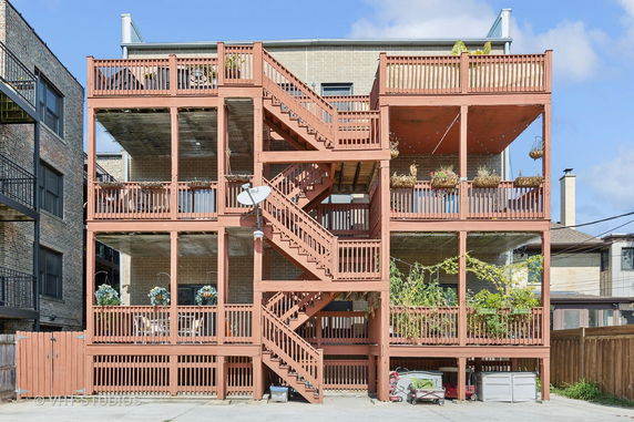 Back view of a multi-story building with wooden balconies and staircases.