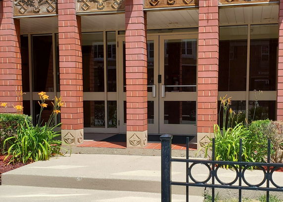 Front view of a building entrance with brick pillars and glass doors.