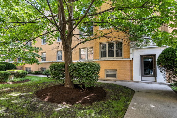 Front view of a brick multi-story residential building with pathway.