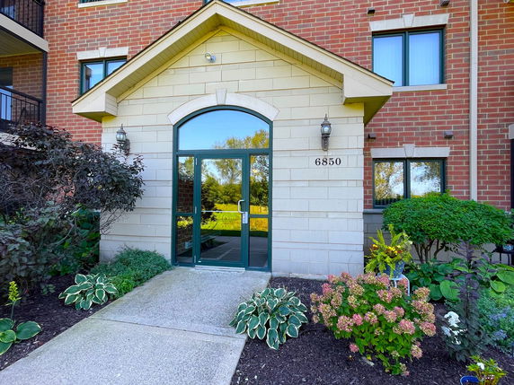Front view of a building entrance with brick exterior and glass door.