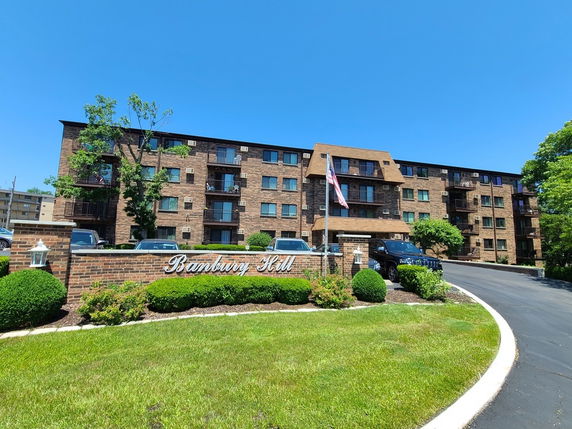 Front view of a multi-story residential building with a brick exterior and balconies.