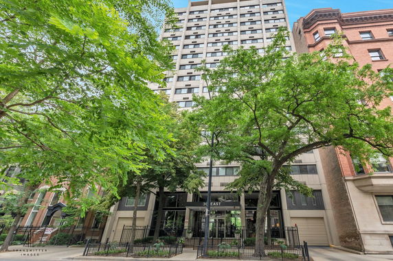 Front view of a multi-story building with a glass entrance and surrounding trees.