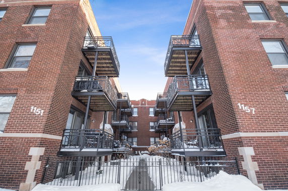 Front view of a brick apartment building with balconies.
