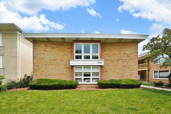 Front view of a two-story brick building with large windows.