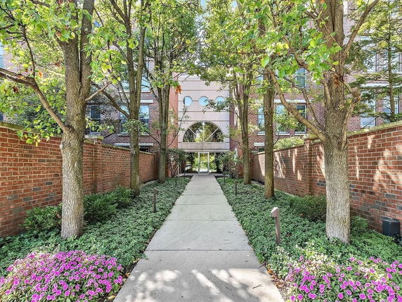 Front view of a building with a pathway leading through a garden and trees to the entrance.