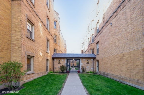 Front view of a brick apartment building with a walkway and entrance.