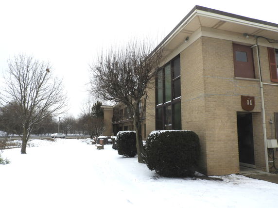 Front view of a two-story brick building with a flat roof and large windows.