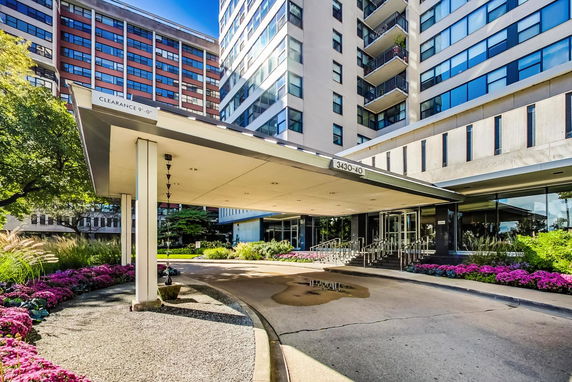 Front view of a multi-story building with a covered entrance and glass doors.