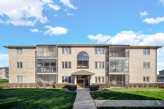 Front view of a three-story apartment building with screened balconies.