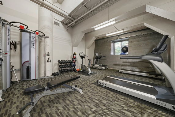 Indoor gym area with exercise equipment including treadmills, stationary bikes, and weight machines.