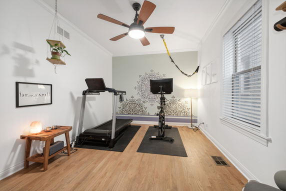 Room with exercise equipment including a treadmill and a stationary bike.